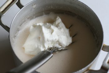 замоченный желатин ввести в смесь, добавить ваниль, взбитые сливки, тщательно размешать и охладить смесь до 25—30°
