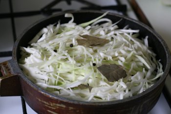 положить капусту в сковороду с жиром, добавить лавровый лист, перец горошком, уксус, можно без уксуса, залить водой или бульоном