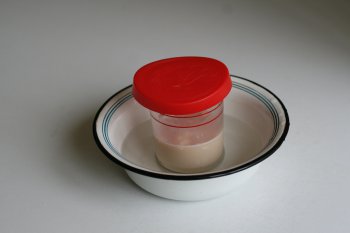 стакан накрыть крышкой и поставить в посуду с теплой водой