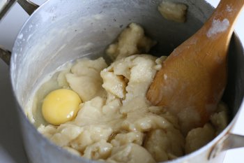 массу слегка охладить и ввести по одному яйца, тщательно их вмешивая в тесто