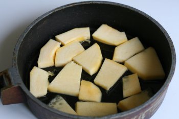 часть тыквы нарезать на дольки и уложить на смазанное жиром дно сковороды