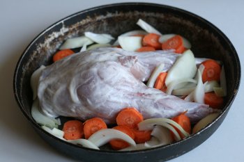 положить кролика на смазанную жиром сковороду, рядом нашинкованные лук и морковь