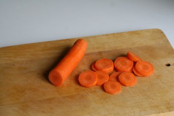 морковь очистить, в кастрюлю с мясом положить коренья, воду довести до кипения, снять пену, варить при слабом кипении 1-1,5 часа
